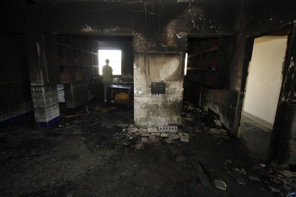 A resident stands inside a burnt mosque in the Bedouin village of Tuba Zangaria