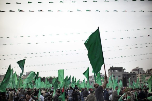 A Palestinian man waves a green Hamas party flag as tens of thousands of supporters of the Islamist movement gather in Gaza City to celebrate the 24th anniversary of its founding.  AFP PHOTO/MARCO LONGARI