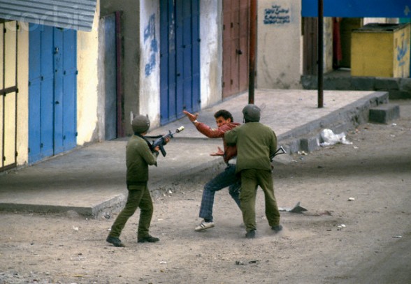 12 Feb 1988, Gaza, Gaza Strip --- Two armed soldiers on patrol arrest a Palestinian man in the streets. Violence broke out after rebel Israeli and Palestinian fighters protested in the occupied territory of Gaza during the first Intifada. --- Image by Patrick Robert/Sygma/CORBIS