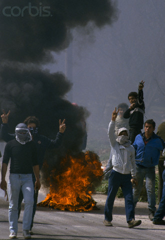 24 Feb 1988, Beit Ummar, West Bank --- While fires burn in the streets of Beit Omar, Palestinian demonstrators give peace signs during an uprising. Violence broke out after rebel Israeli and Palestinian fighters protested in the disputed territory of West Bank during the first Intifada. | Location: Beit Omar, West Bank.  --- Image by Patrick Robert/Sygma/CORBIS