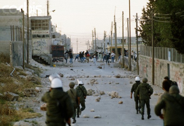 22 May 1990, Shu'fat, East Jerusalem, West Bank --- Israeli soldiers approach a group of rioting Palestinians in Shufat, Jerusalem. The riot is in response to a shooting by a discharged Israeli soldier that occurred two days before in Rishon le-Ziyyon, which killed eight Palestinian laborers and wounded nine others. --- Image by Patrick Robert/Sygma/Corbis