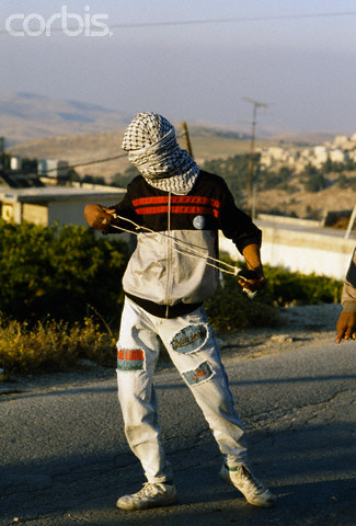 22 May 1990, Shu'fat, East Jerusalem, West Bank --- A masked Palestinian man carries a sling used to fling rocks during a riot in Shufat, Jerusalem. The riot is in response to a shooting by a discharged Israeli soldier that occurred two days before in Rishon le-Ziyyon, which killed eight Palestinian laborers and wounded nine others. --- Image by Patrick Robert/Sygma/Corbis