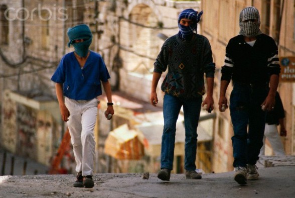 April 1989, Bethlehem, West Bank --- Masked  young men of the Intifada carry stones with them in preparation for a riot in Bethlehem. --- Image by Ricki Rosen/CORBIS SABA