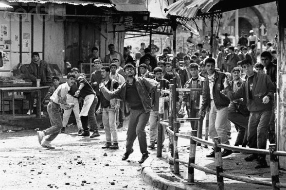 ca. 1988 - 1992, Khan Yunis, Gaza Strip --- A group of young Palestinian men hurl stones at Israeli soldiers in the town of Khan Yunis in the Gaza Strip. --- Image by David H. Wells/CORBIS