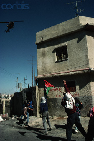 1988, West Bank --- Palestinian guerrillas throw rocks and make defiant gestures at a helicopter of the the occupying Isreali military forces. --- Image by Peter Turnley/CORBIS