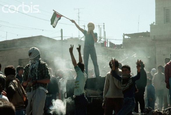 1988, West Bank --- Young Palestinian freedom fighters give the sign for liberation and wave a flag during a riot against the occupying Israeli soldiers. --- Image by Peter Turnley/CORBIS