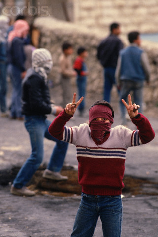 1988, West Bank --- A young Palestinian boy makes a hand signal symbolizing the Palestinian fight against Israeli occupation. --- Image by  Peter Turnley/CORBIS