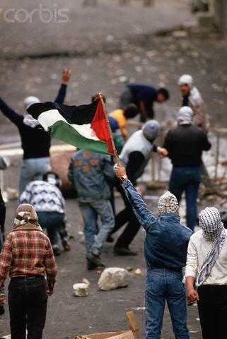 1988, Nablus, West Bank --- Masked Palestinians hold a flag and throw rocks at Israeli soldiers. --- Image by Peter Turnley/CORBIS