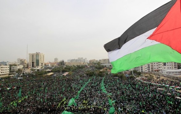 A Palestinian flag flutters as thousands