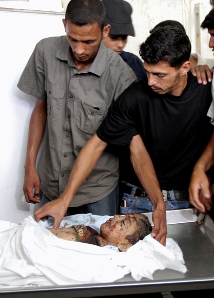 Palestinians look at the body of six-year-old Palestinian, Ali al-Shawaf at the Nasser hospital morgue in Khan Yunis, in the southern Gaza Strip on June 23, 2012 after he was killed during Israeli air strikes in Gaza. Two others were wounded in the shelling, but the Israeli military denied it was responsible. AFP PHOTO/ SAID KHATIB