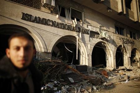 A Palestinian walks past the Islamic National Bank after it was destroyed in what witnesses said was an Israeli air strike in Gaza City November 20, 2012. International pressure for a ceasefire in the Gaza Strip puts Egypt's new Islamist president in the spotlight on Tuesday after a sixth day of Palestinian rocket fire and Israeli air strikes that have killed over 100 people. REUTERS/Suhaib Salem