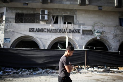 Palestinians look at the Islamic National Bank after it was destroyed in what witnesses said was an Israeli air strike in Gaza City November 20, 2012. International pressure for a ceasefire in the Gaza Strip puts Egypt's new Islamist president in the spotlight on Tuesday after a sixth day of Palestinian rocket fire and Israeli air strikes that have killed over 100 people. REUTERS/Ahmed Jadallah