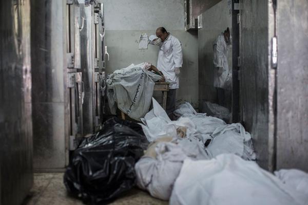 A doctor cries while standing next to a table with the bodies of four dead children in Shifa hospital in #Gaza - Photovia  ‏@m_househ 
