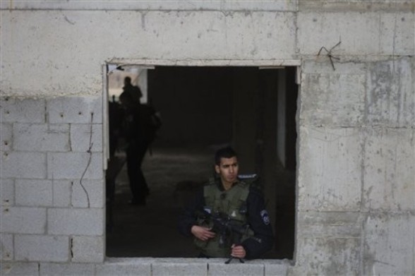 An Israeli riot policeman guards from a building along the border between Majdal Shams in the Golan Heights, and Syria, as security is tightened ahead of Land Day,Friday, March 30, 2012. March 30 is traditionally marked by Israeli Arabs as "Land Day," a time of protests against the confiscation of Arab-owned lands by Israel. In recent years, Palestinians have joined in. (AP Photo/Ariel Schalit)