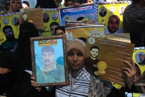Palestinians hold posters of jailed Palestinian football player Mahmud Sarsak and prisoner Akram Rikhawi during a rally in solidarity with two Palestinian prisoners detained by Israel and still on hunger strike in Gaza City on June 11, 2012. AFP PHOTO/MAHMUD HAMS