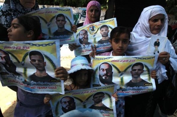 Palestinians hold posters of jailed Palestinian football player Mahmud Sarsak and prisoner Akram Rikhawi during a rally in solidarity with two Palestinian prisoners detained by Israel and still on hunger strike in Gaza City on June 11, 2012. AFP PHOTO/MAHMUD HAMS